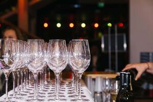 Line of empty wine glasses at a bar with lights in background photo