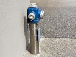 Blue fire hydrant attached to a wall in urban setting photo