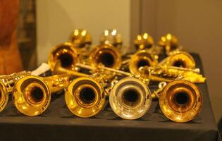 Array of brass and silver trumpets on black table display photo
