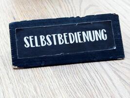 Black selbstbedienung sign on wooden surface photo
