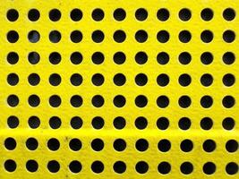 Yellow perforated surface with uniform circular patterns for industrial design photo