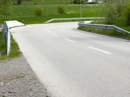 Empty country road with green fields and guardrails in serene landscape photo
