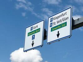 Austrian highway signs for klagenfurt and st. veit glan under blue sky with clouds photo