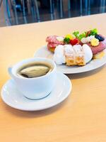 Black coffee with assorted pastries on plate in bright cafe setting photo
