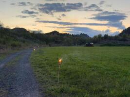 Sunset field with torches and winding path in lush countryside photo