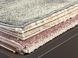 Stack of layered textured carpets with varied patterns and colors for interior design photo