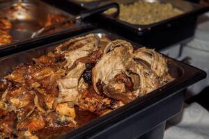Delicious roast pork ribs served at buffet with cooked vegetables in background photo