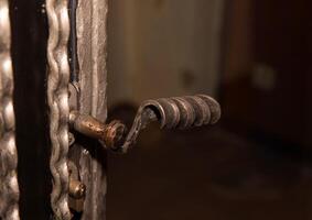 Close-up of a rustic metal door handle with intricate design and patina texture photo