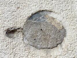Close-up of weathered concrete wall surface with exposed patch photo