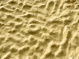 Textured yellow surface with wavy patterns and shadows photo