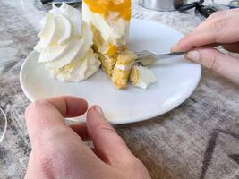 Adult enjoying citrus cake with whipped cream and fork on marble table photo