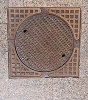 Old rusty sewer hatch on an old metal plate. View from above. photo
