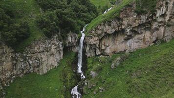 Aerial zoom out hidden waterfall cascades down a remote cliff side Caucasus Mountains of Georgia.Wilderness, tranquil scene the raw beauty. Mist rises gently as water flows into a forested ravine video