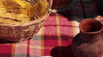 Pour coffee into mugs from french press, add milk from clay jug and put sugar. Process of making coffee at picnic. Rustic style picnic still life with woven baskets on plaid blanket video