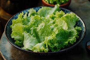 A bowl of lettuce sitting on a table photo