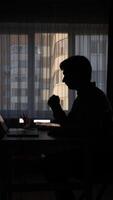 vertical silhouette of man coughing at desk in office video