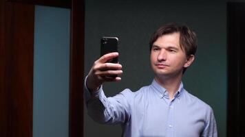 Office worker taking a selfie with smartphone in office corridor video
