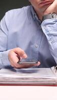 vertical Bored office worker browsing smartphone at desk with stack of folders video