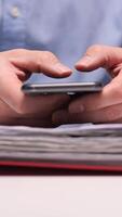 vertical Office worker browsing smartphone with documents and files in background video
