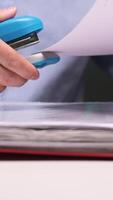 vertical Office worker stapling documents to a folder using a blue stapler video