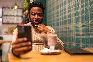 Frustrated African American male looking annoyed and angry while explaining something during phone discussion at the bar. photo