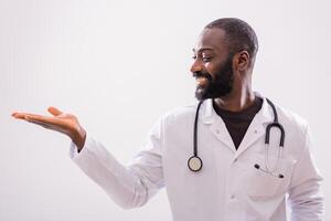 Portrait of cheerful black doctor who is showing palm of hand on gray background. Copy space for your text or advertisement. photo