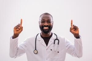 Portrait of smiling African doctor who is pointing upside on the gray background. Copy space for your text or advertisement. photo