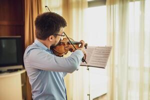 Violinist performing on violin in a warmly lit room, professional musician showcasing his skill. photo