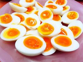 Many boiled duck eggs sliced on the pink plastic plate or dish. Diet and Healthy food photo