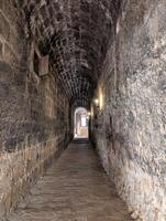Historic stone corridor featuring aged walls and cobblestone floor, illuminated by soft lights, inviting exploration in a quiet location photo
