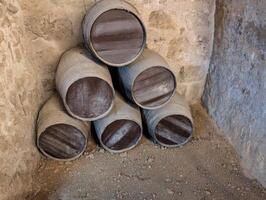 Stacked wooden barrels in a rustic stone cellar located in a historic winery, showcasing traditional fermentation practices and age old craftsmanship photo