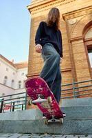 Low angle view of skateboarder balancing on pink skateboard. Close up of underside of deck and wheels of skateboard on stairs at city street photo