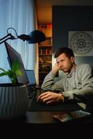 Man procrastinating at workplace while browsing on computer photo