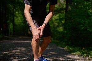 Man suffering from knee pain during running in park photo