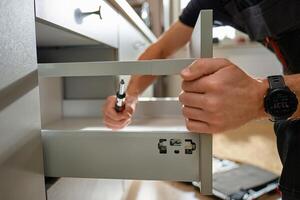 Carpenter installing drawer front in modern kitchen cabinet photo