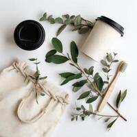 Reusable coffee cup, bamboo toothbrushes, and cotton bag with green leaves photo