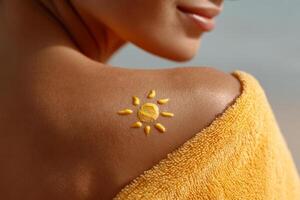 Sun drawn with sunscreen on tanned female shoulder photo