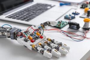 Mechanical robotic hand assembled from plastic components and wires on work desk at home photo
