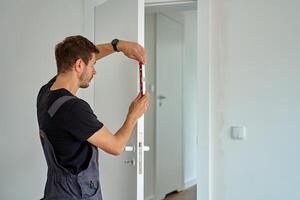 Man using spirit level to align door frame during installation photo