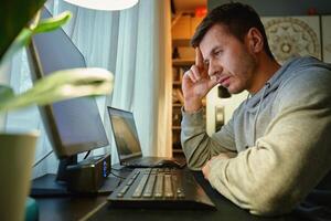 Man procrastinating at workplace while browsing on computer. Freelancer distracted at home offic photo