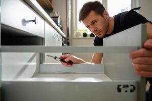 MaleCarpenter installing and adjusting drawer front in kitchen cabinet c photo