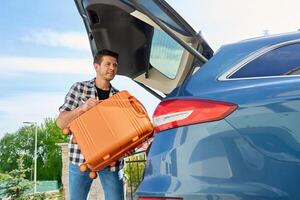 Man loading suitcase into car trunk photo