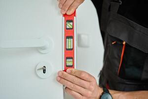 Close up of carpenter Checking Door Alignment with Spirit Level photo