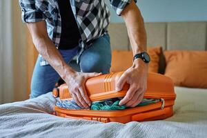 Man packing suitcase with clothes, preparing for travel photo