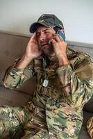 vertical Depressed soldier crying while making a phone call at home photo