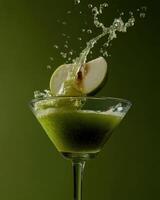 Green apple slice splashing into cocktail glass with matching green backdrop photo