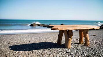 Rustic Wooden Table on Pebble Beach Shore and blue water photo