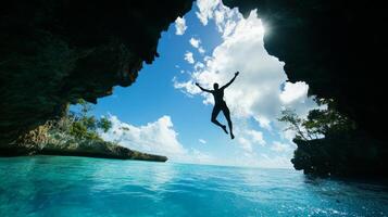 Traveler jumps into sparkling blue lagoon from a high cliff on a summer vacation photo