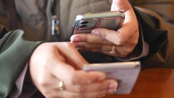 Hands engaged in texting and note-taking at a cafe video