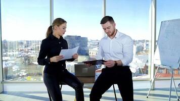 Business man and woman speaking about new project. Attractive woman and handsome man showing different graphics and talk about business in modern office. video